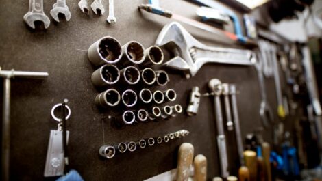Various workshop tools, including wrenches and sockets, hang on a wall organizer.